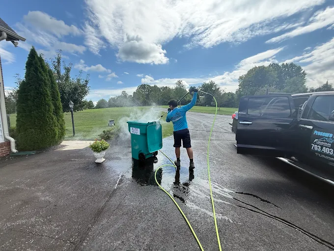 Technician cleaning and sanitizing a residential trash bin