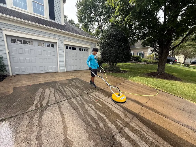Technician pressure washing concrete with a rotary surface cleaner